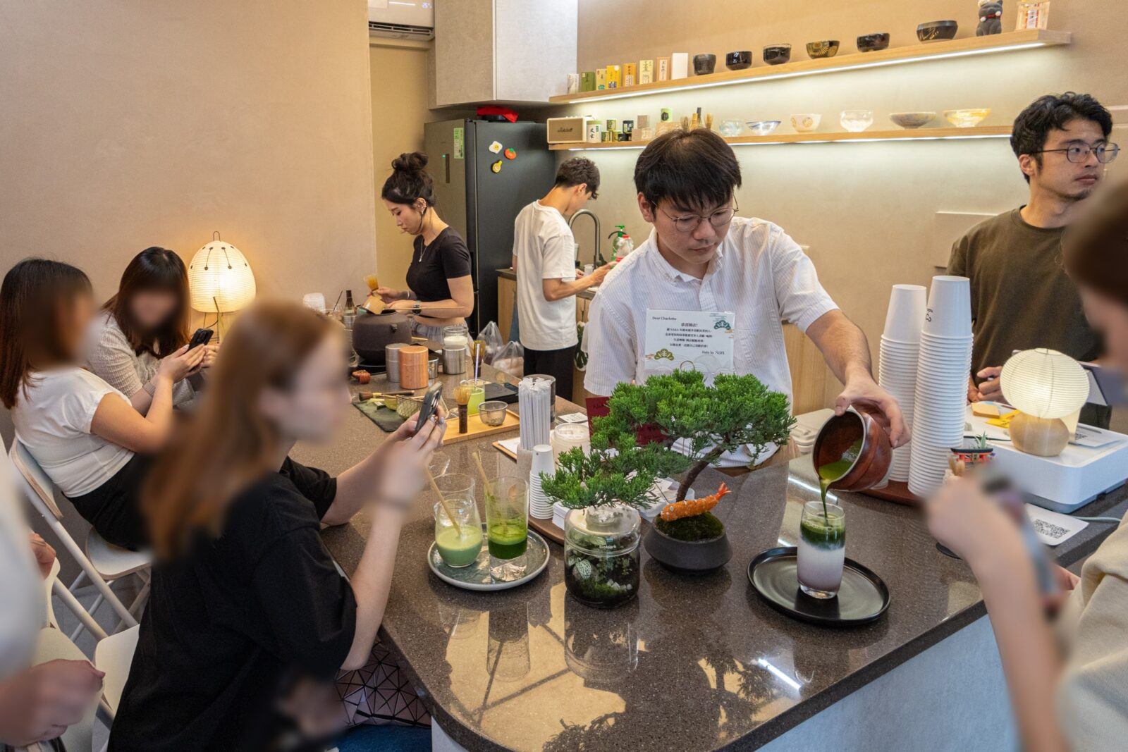 店內吧台與座位區，店員現場手刷抹茶並製作飲品，吧台前可近距離觀看沖刷過程。