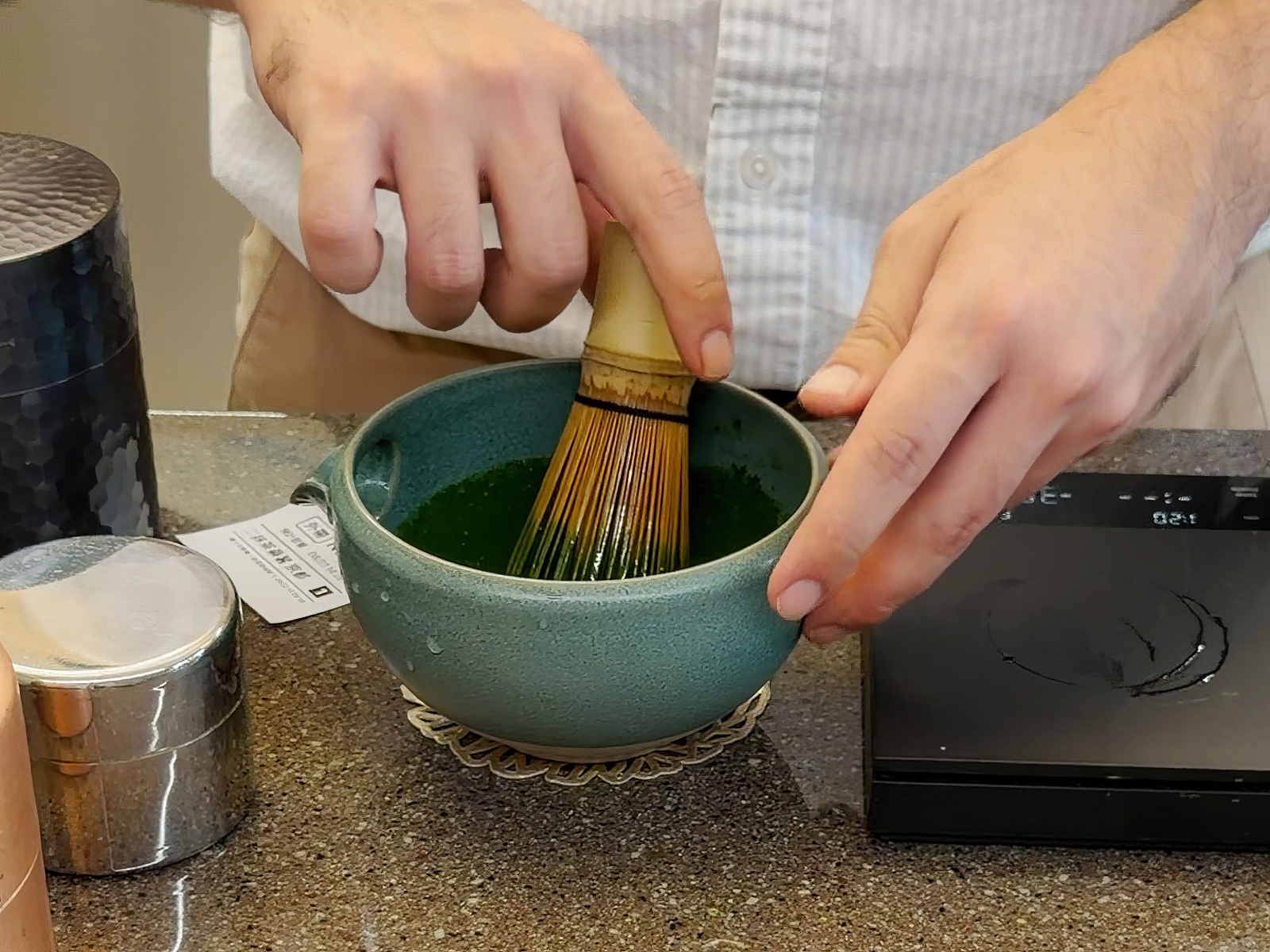 店員使用茶筅在茶碗中現場手刷抹茶，呈現細緻的抹茶製作過程。