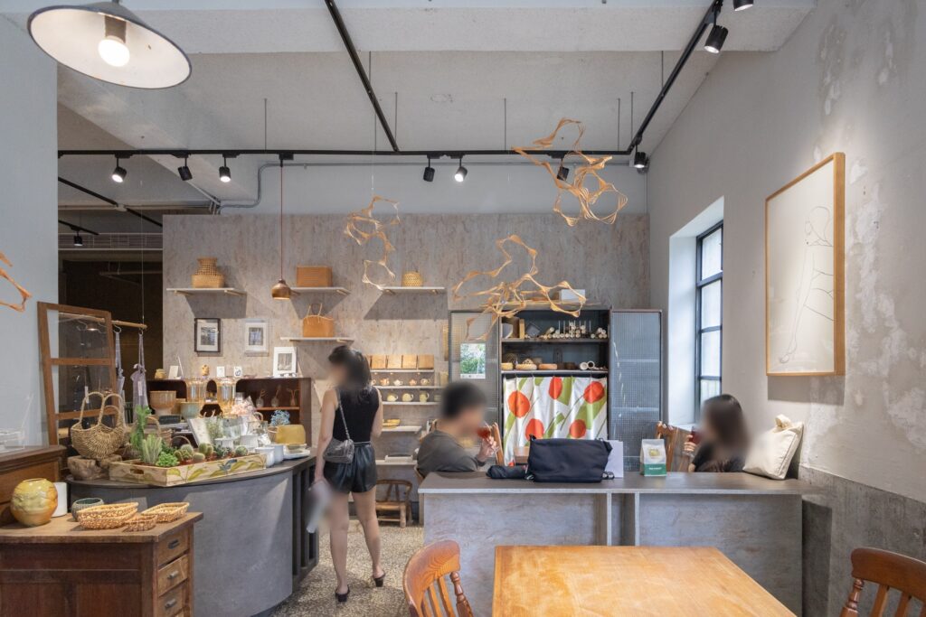 店內座位與工藝展示空間，灰色水泥牆搭配木質家具、竹編作品與選物陳列，呈現咖啡與工藝融合的空間特色。