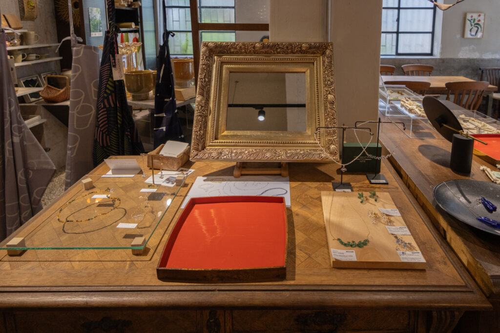 店內選物展示桌，陳列手作飾品、項鍊、耳環與設計小物，搭配復古鏡框與木質桌面，呈現藝術選物氛圍。