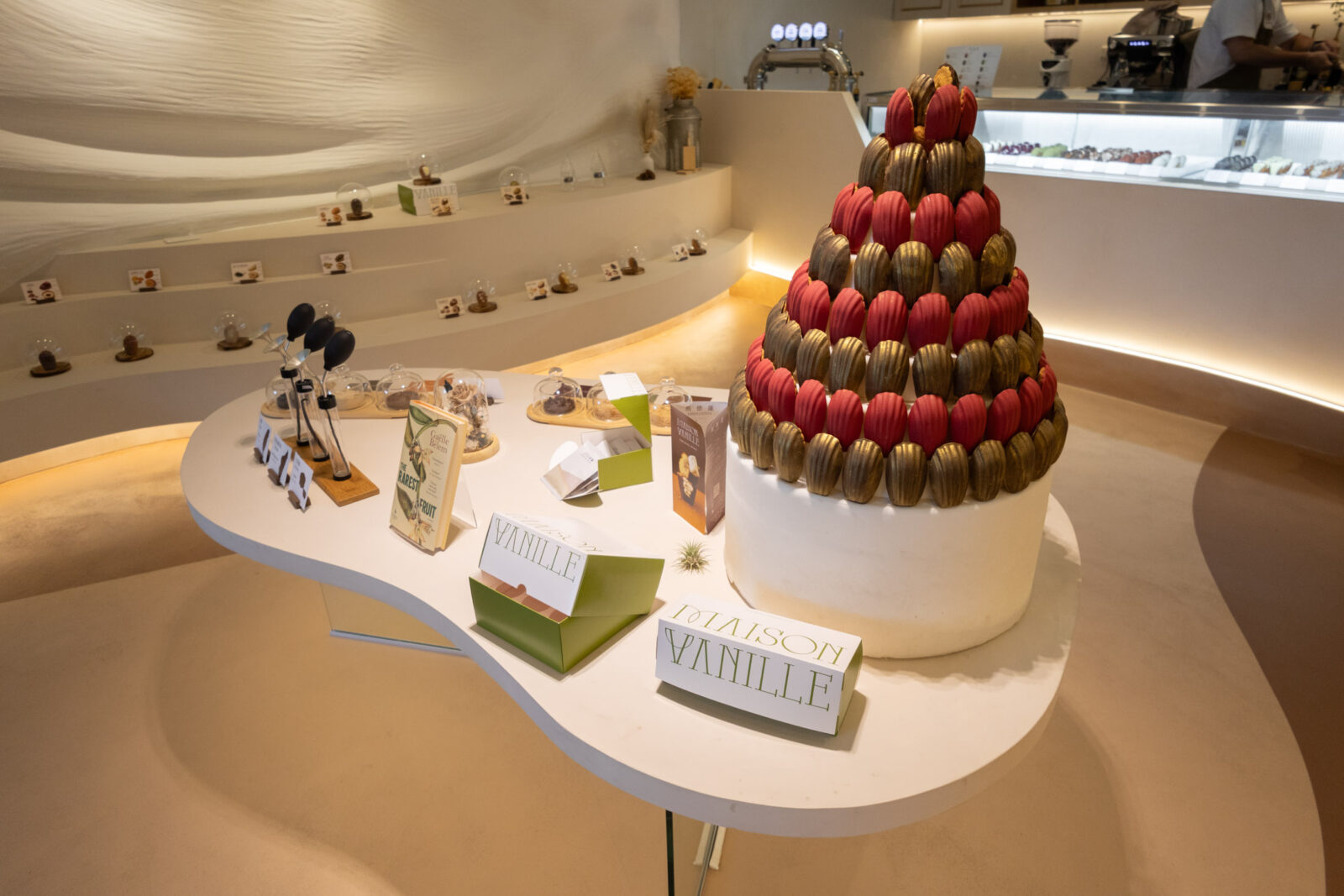 Maison Vanille 店內中央展示區，以紅金色瑪德蓮堆疊成甜點塔，周圍陳列香草與食材介紹。