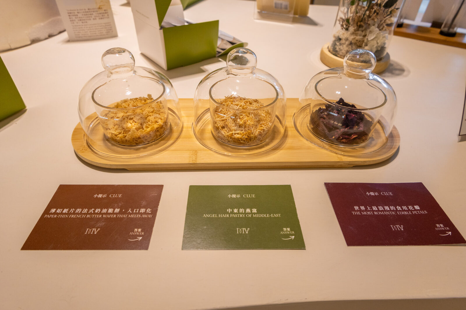 Maison Vanille 店內食材聞香展示，玻璃罩內陳列薄如紙片的法式奶油脆餅、中東燕窩與可食用玫瑰花瓣。