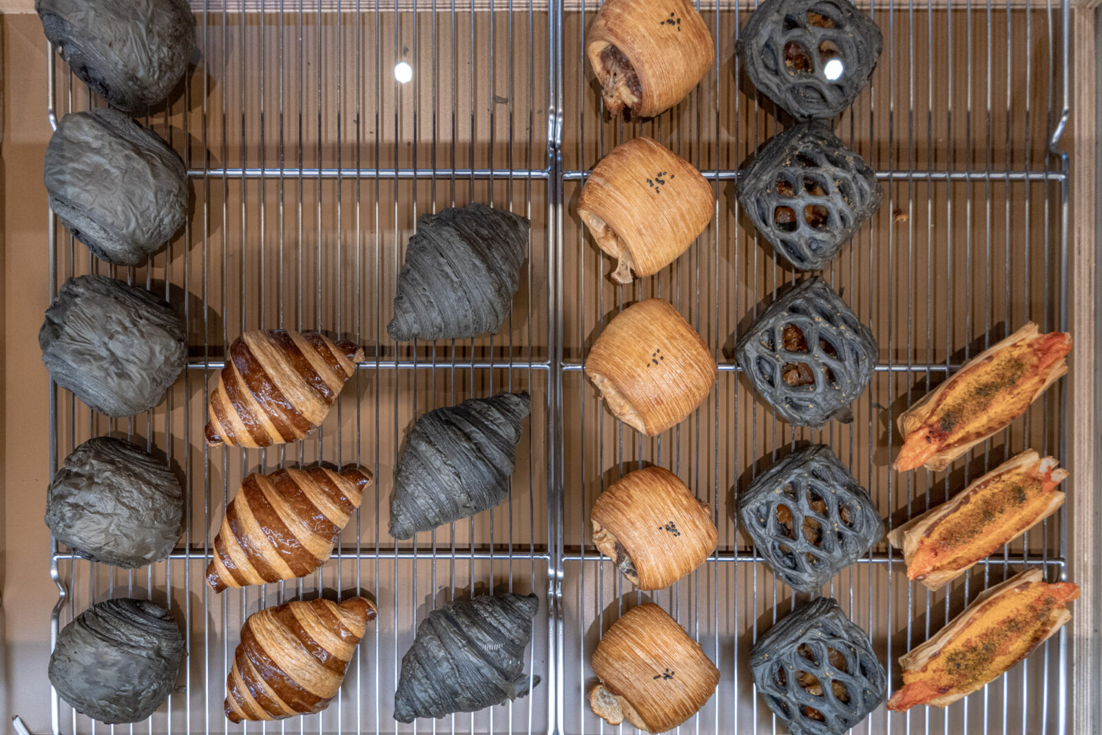 Muhei Bakery 暮黑烘焙可頌櫃俯視，多款金黃與竹炭色甜鹹可頌整齊陳列於架上