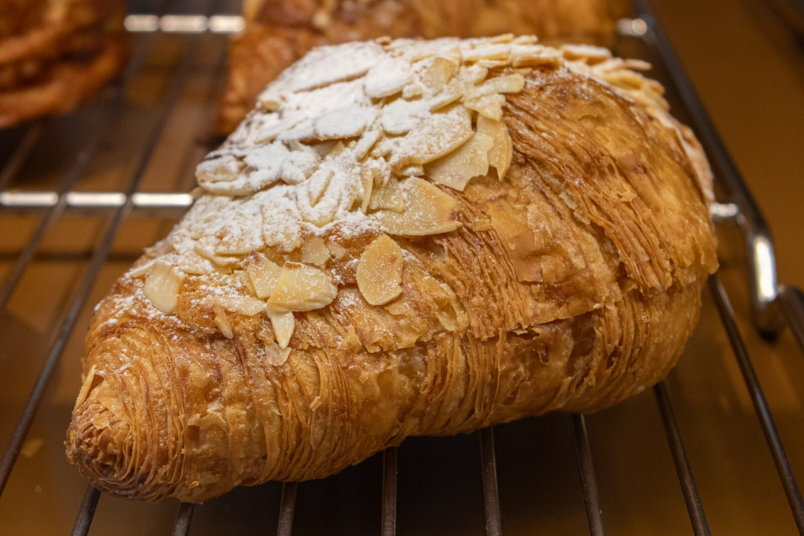 Muhei Bakery 暮黑烘焙杏仁可頌近拍，金黃酥皮上鋪滿杏仁片與糖粉