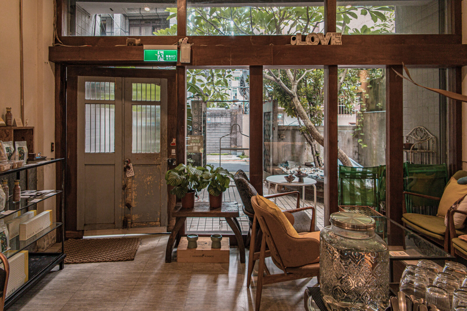 SUGARbISTRO 小食糖一樓店內一隅，可看到老宅木框、庭院綠意與復古座椅