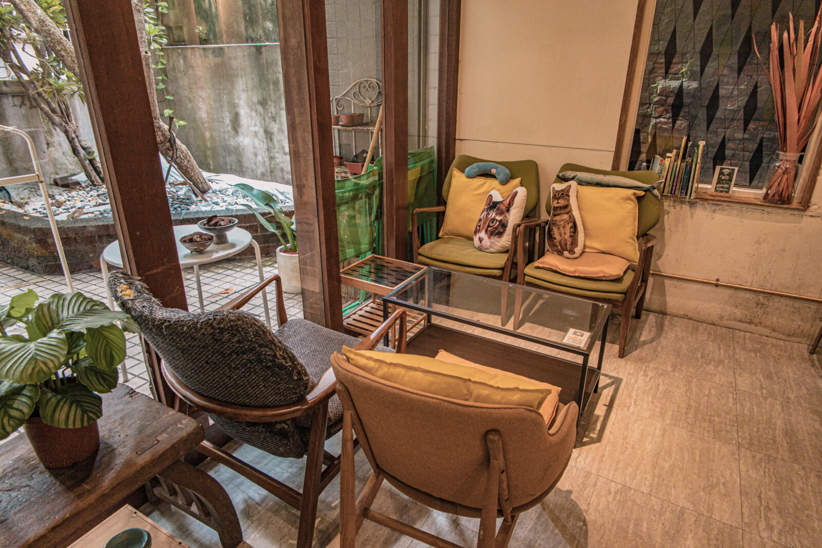 SUGARbISTRO 小食糖一樓靠庭院座位區，復古單椅、貓咪抱枕與綠意窗景