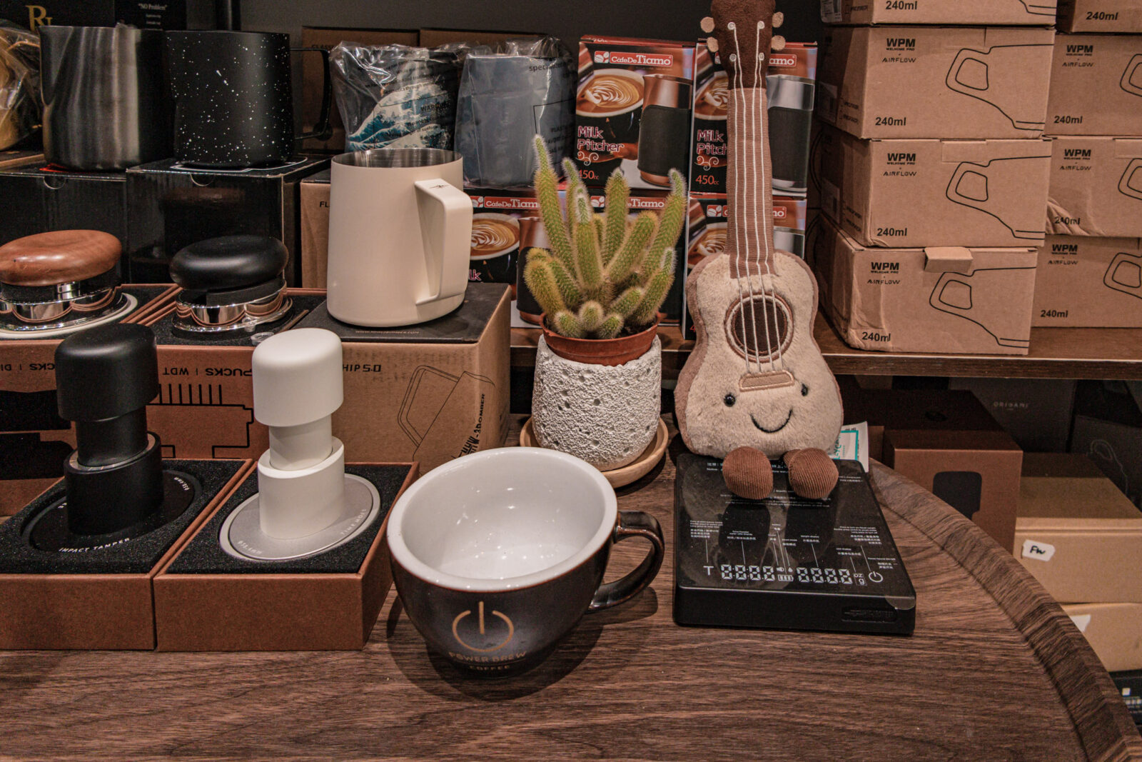 Lee’s Coffee 古亭店咖啡器具展示,桌上擺有拉花杯、壓粉器、咖啡杯與吉他造型娃娃