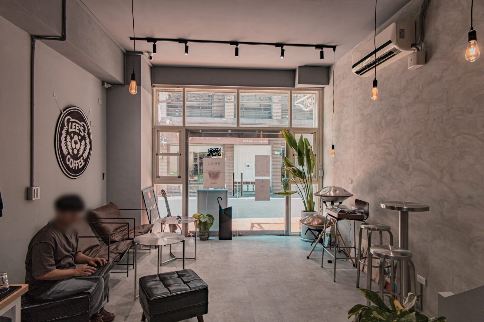 Lee’s Coffee 古亭店座位區,灰色系空間搭配沙發、高腳椅與大片落地窗,店內可見 Lee’s Coffee 招牌與音樂元素